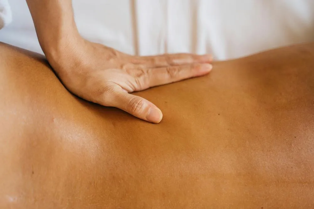 A person lying on a massage table receiving a Swedish massage