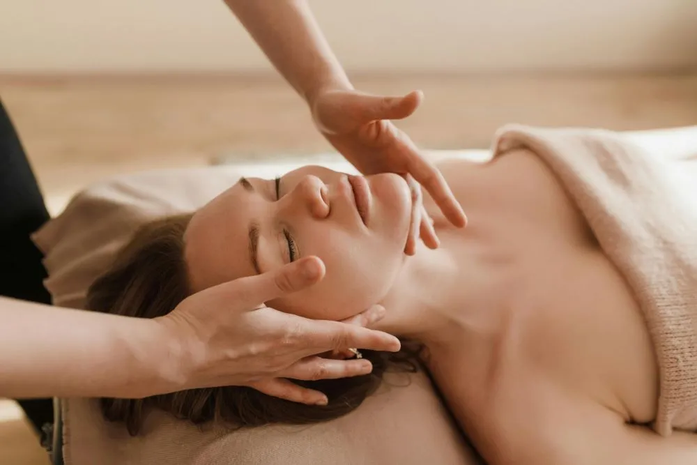 A therapist performing TMJ massage on a client's jaw.